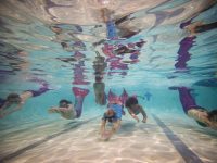 BOURNEMOUTH, ENGLAND - AUGUST 19: Mermaiding students swim in their tails during a Mayim Mermaid Academy lesson at the swimming pool at Bournemouth Collegiate School on August 19, 2017 in Bournemouth, England. The ancient Assyrian goddess Atargatis is thought to be one of the earliest mermaids and like Ea, the Babylonian god of the sea from around 4000bc, she had the upper body of a human and the lower body of a fish. Throughout history Merfolk have been popular in art and literature. A well known Hans Christian Anderson fairy tale "The Little Mermaid" (1836) was adapted to an animated film in 1990 and is still popular today. Recently the practice of mermaiding has become popular across the world as an extreme sport and cosplay/performance art. Mermaiding involves the wearing of a costume mermaid tail, consisting of a plastic monofin covered in a fabric, while swimming or performing. The practice of mermaiding has been taught by professional instructors in the UK since 2006. (Photo by Jack Taylor/Getty Images)